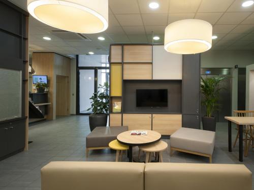 a lobby with a couch and a table and chairs at B&B HOTEL Lyon Ouest Tassin in Tassin-la-Demi-Lune