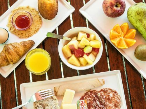 ein Tisch mit verschiedenen Frühstücksspeisen auf Tellern in der Unterkunft Ibis Château-Thierry in Essômes-sur-Marne