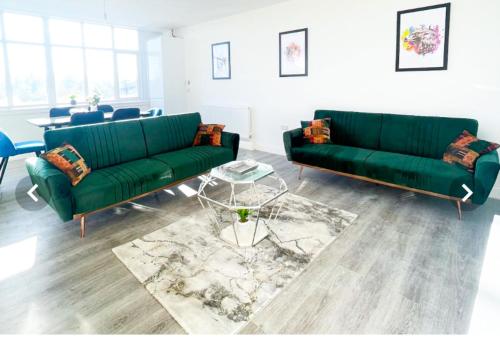 a living room with two green couches and a table at The Felix Apartments in Flitwick