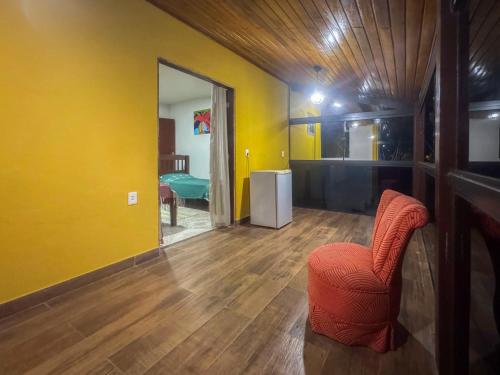 a room with an orange chair and a yellow wall at Aconchego da Lu in Angra dos Reis