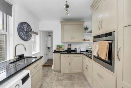 a kitchen with white cabinets and a clock on the wall at Wherstead Rd House By Homestyles Hosts Short Lets & Serviced Accommodation Suffolk With Free Parking in Ipswich