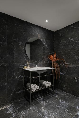 a black bathroom with a sink and a mirror at Mythical Coast Wellness Retreat in Mytilene