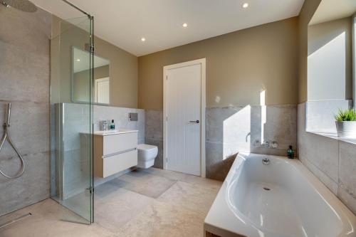 een badkamer met bad, douche en toilet bij Harbour Heights Seahouses in Seahouses