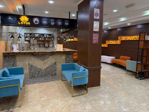 un vestíbulo de un hotel con sillas azules y un bar en The Grand Mirage Hotel, en Ma‘ābīlah
