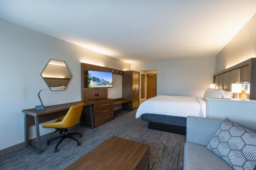 a hotel room with a bed and a desk and a couch at Holiday Inn Express & Suites Greenwood Mall by IHG in Greenwood