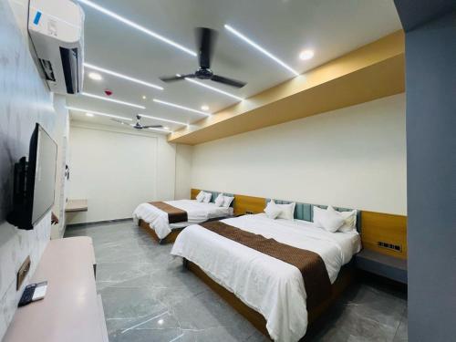 Una habitación de hotel con dos camas y un televisor de pantalla plana. en Hotel Sun Palace, en Somnath