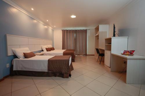 a hotel room with two beds and a desk at Ita Park Hotel in Itá