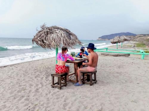 a group of people sitting at a table on the beach at La Fogata Bungalows in Machalilla