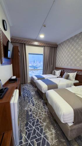 a hotel room with three beds and a television at فندق البارون الذهبي in Az Zāhir