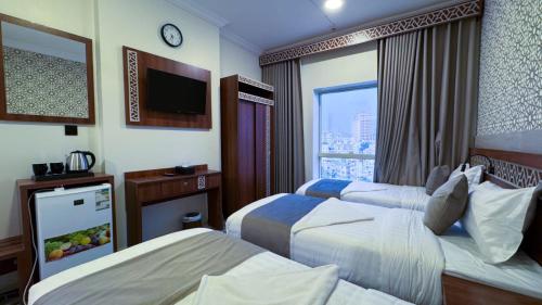 a hotel room with two beds and a tv at فندق البارون الذهبي in Az Zāhir
