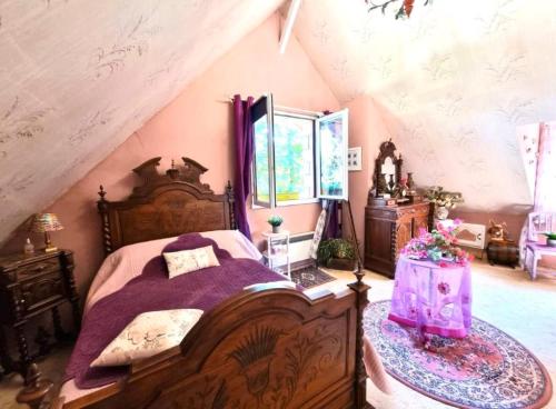 a bedroom with a large wooden bed with purple sheets at Les bosquets chambre d hôtes in Caugé