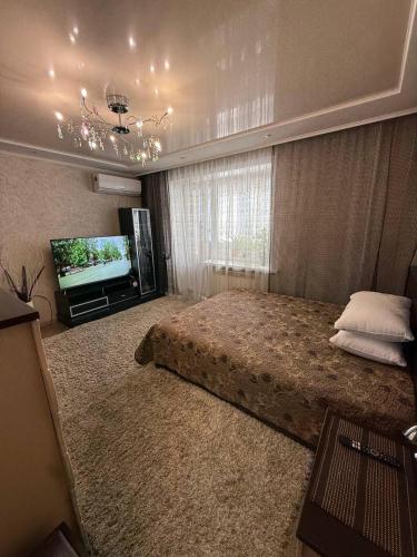 a bedroom with a bed and a flat screen tv at Апартаменты на СОВЕТСКОЙ 39 in Petropavlovsk