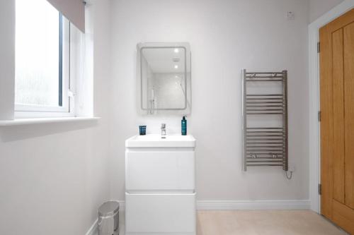 a white bathroom with a sink and a mirror at Cherry Lodge by Escape Ordinary in Coleraine