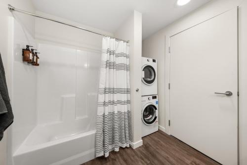 a bathroom with a washing machine and a shower curtain at 2BR Cozy Apartment in DT in Spokane