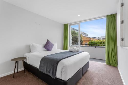 een slaapkamer met een bed en een groot raam bij QV Stays Modern Spacious Multi-Level Townhouse in Auckland