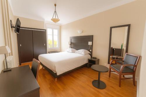 a bedroom with a bed and a table and a chair at Hotel De L'Europe in Toul
