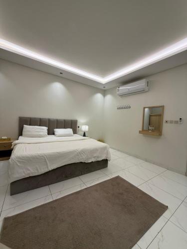 a white bedroom with a large bed and a mirror at شقة فاخرة in Al Kharj