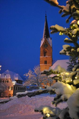 a church steeple with a clock tower in the snow at B&B Apart Hotel Goldener Hahn - Hygge Pool & Sauna in Baiersbronn