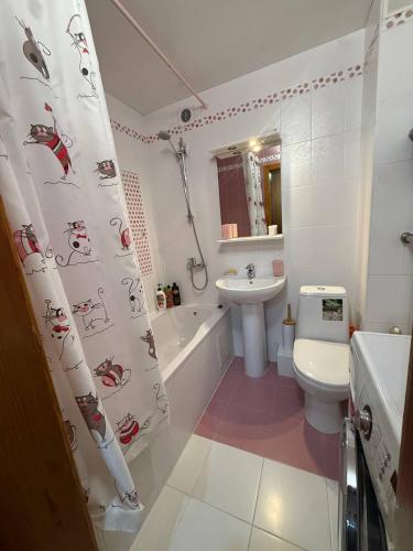 a bathroom with a sink and a toilet and a shower curtain at Апартаменты на СОВЕТСКОЙ 39 in Petropavlovsk