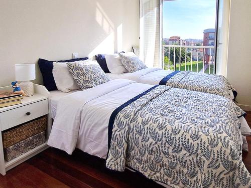 two beds in a bedroom with a window at Apartamento, zona residencia con piscina, cerca de las playas en Santander in Santander