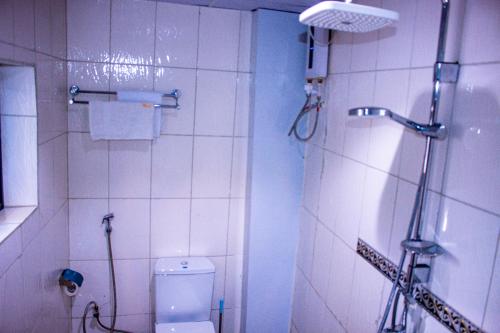 a white bathroom with a shower and a toilet at West Hotel Douala in Bonabéri