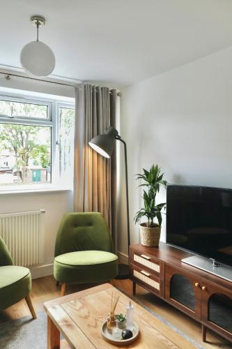 a living room with a television and a green chair at Modern Flat In Penge - 3 person in Elmers End