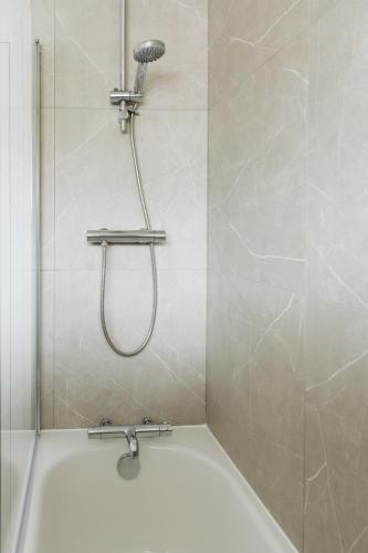 a shower with a shower head in a bathroom at Modern Flat In Penge - 3 person in Elmers End