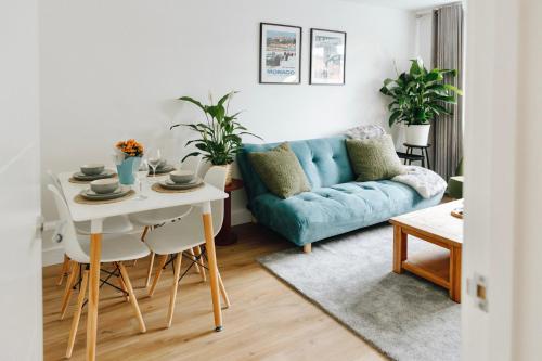 Una sala de estar con un sofá azul y una mesa. en Modern Flat In Penge - 3 person, en Elmers End