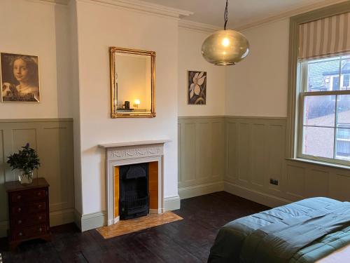 a bedroom with a fireplace and a mirror on the wall at The Saltburn Townhouse in Saltburn-by-the-Sea