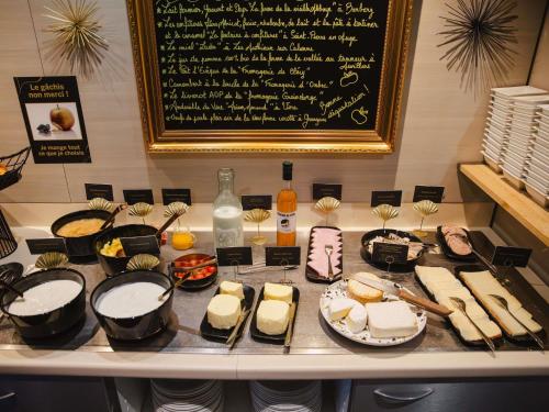 Una mesa con diferentes tipos de postres y una pizarra. en Mercure Cabourg Hôtel & Spa, en Cabourg