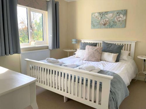 una camera da letto con una culla bianca e un letto con cuscini di SALTKETTLE - Blakeney a Blakeney