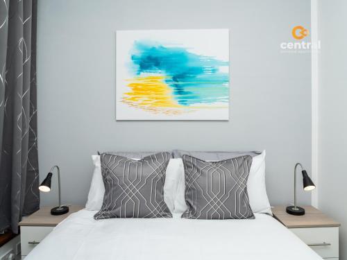 ein Schlafzimmer mit einem weißen Bett und einem Gemälde an der Wand in der Unterkunft Trades Lane by CENTRAL SERVICED APARTMENTS - Cosy 1 Bedroom - Central Location - Walk Away from Waterfront - Walk Away to Bus & Train Station - Long Stays Welcome in Dundee