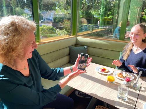 a woman sitting at a table taking a picture with her cell phone at Mercure Niort Marais Poitevin in Niort