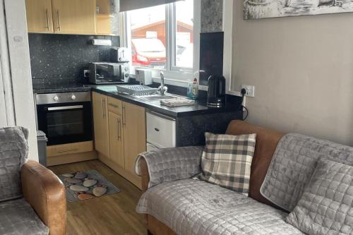 a kitchen with a couch and a stove top oven at 2Bed Chalet Sleeps 4- Garden Balcony Pets Beach in Bridlington
