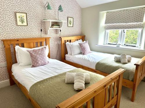 a bedroom with two beds and a window at Plum Tree Cottage, Burnham Market By Together Travel in Burnham Market