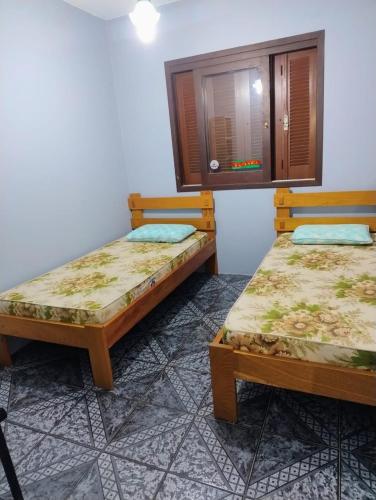 two beds sitting next to each other in a room at Apartamento térreo Torres centro in Torres