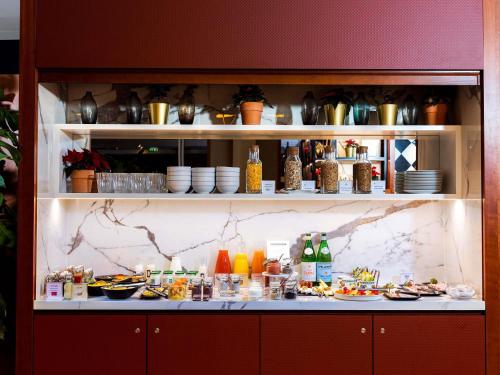 Un mostrador con platos de comida y bebidas. en Sofitel Luxembourg Europe, en Luxemburgo