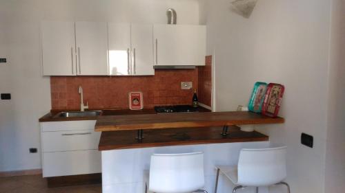 レ・グラツィエにあるAppartamento da Annamariaの白いキャビネットと白いスツール2つ付きのキッチン