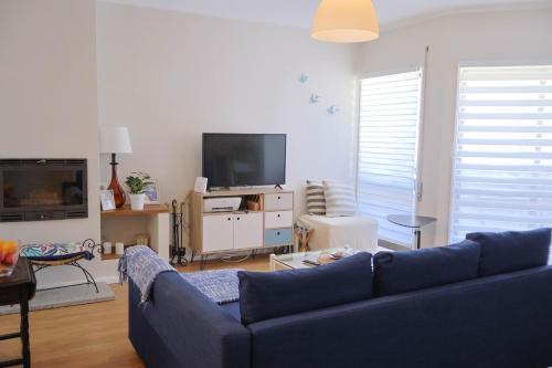 a living room with a blue couch and a tv at Areia StayInn Beach Apartment in Árvore