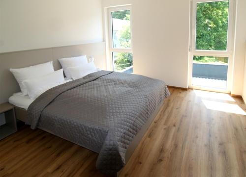 Un dormitorio blanco con una cama y dos ventanas. en Gästehaus Falken, en Hechingen
