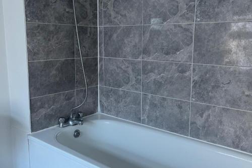a bath tub in a bathroom with a tile wall at 2Bed Sleeps 3 - Central Near Train Station Wifi in Dartford