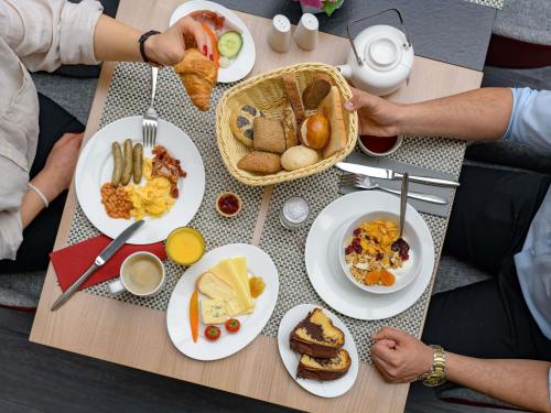 um grupo de pessoas sentadas à mesa com comida para o pequeno-almoço em Mercure Hotel Stuttgart Airport Messe em Estugarda