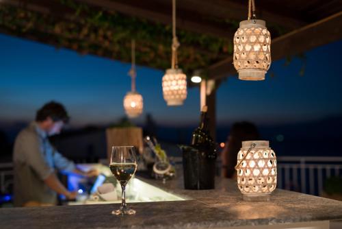 a glass of wine sitting on a bar with lights at Lido Hotel in Xylokastron