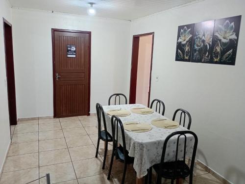a dining room with a table and chairs and a door at Quartos Morumbi in Foz do Iguaçu