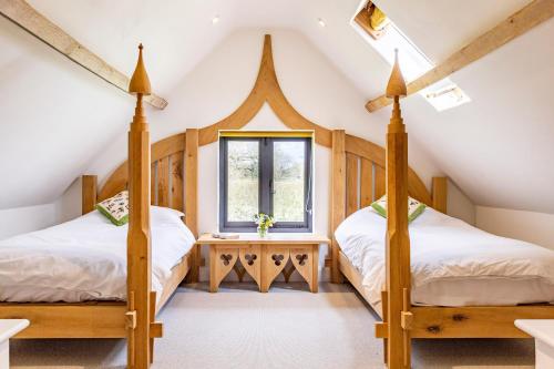 two beds in a attic bedroom with a window at Johnsons Smallholding in Longford