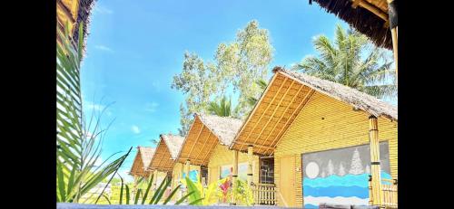 a yellow house with a thatched roof at Bliss Hampi Eco Resort in Hampi