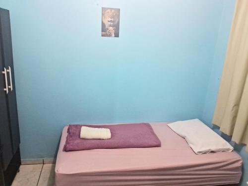 a blue room with a bed with a towel on it at Quartos Morumbi in Foz do Iguaçu