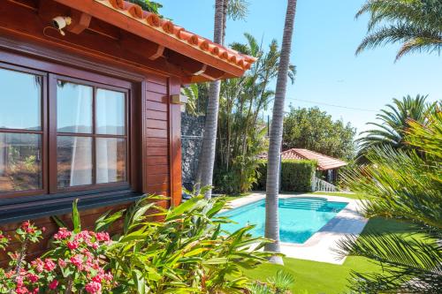 a house with a swimming pool and palm trees at Wooden House with Private Pool Lush Garden in La Laguna