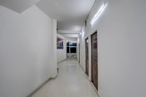 a hallway with white walls and white tile floors at SPOT ON New Hamsafar in Jhūsi
