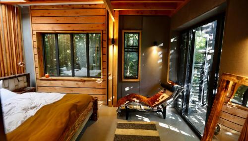 a bedroom with a bed and a large window at Zero Zero Treehouse in Coleford
